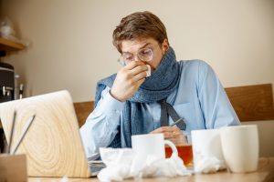 Sick man while working in office, businessman caught cold, seasonal flu.